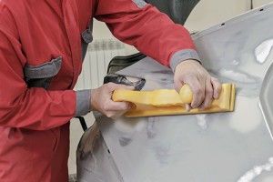 Car painter prepares the rear wing of the car for painting.